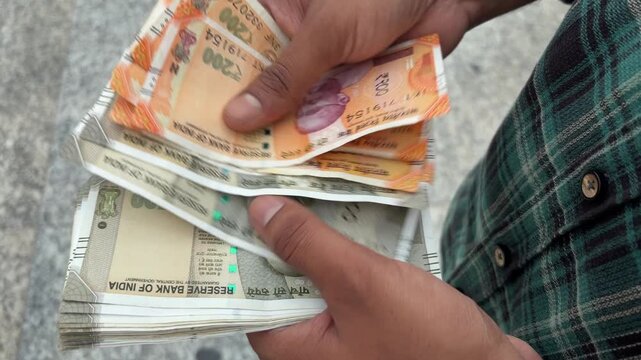 Close up shot of an Indian man counting cash outdoors, male hands holding and counting Indian currency cash, finance and investment concept