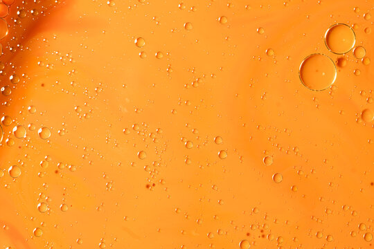 Abstract macro of oil drops in water on bright orange background