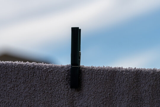 Dark clothes peg hanging laundry to dry outdoors on a sunny day