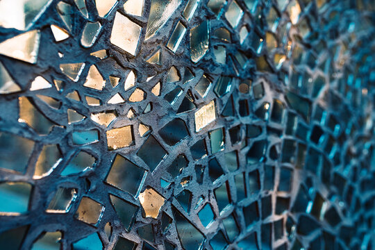 Detailed macro view of a decorative wall mosaic made from shattered mirror glass shards embedded in grey concrete