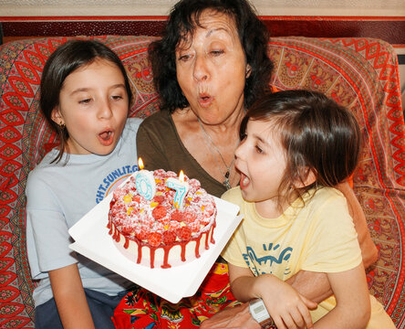 Family birthday with cake celebration. Senior woman