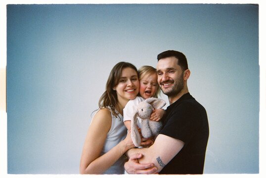 Family poses together in a studio with a child crying