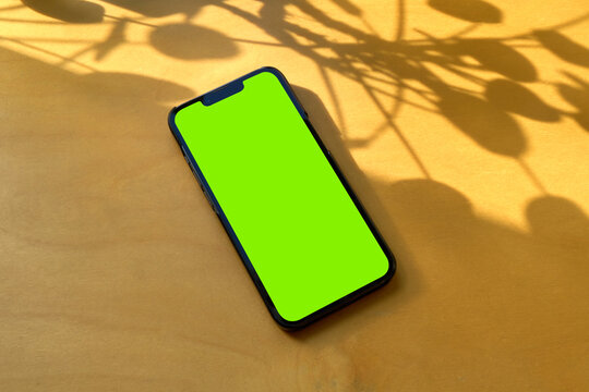 Smartphone with blank isolated screen on wooden table with copy space