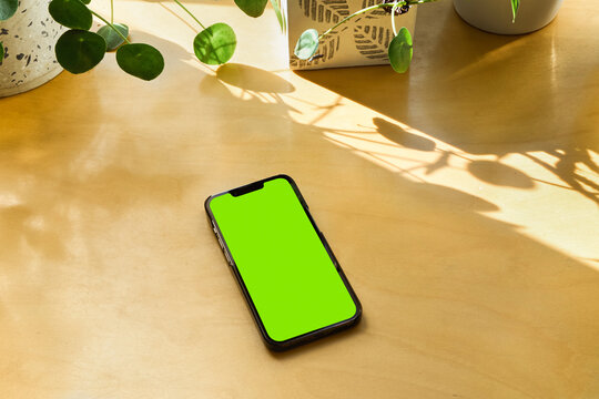 Smartphone with blank isolated screen on wooden table with copy space