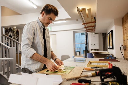 Craftsman framing artwork in his creative workshop studio