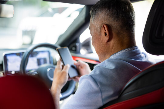 Man using a smartphone while sitting in the driver's seat