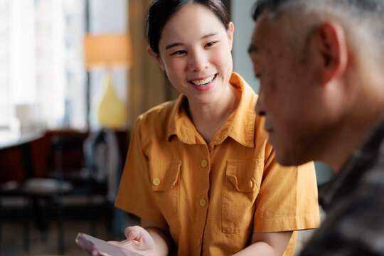 Smiling woman shows something on mobile phone to older man.