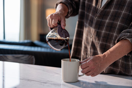 Pouring coffee into a mug on a marble countertop.