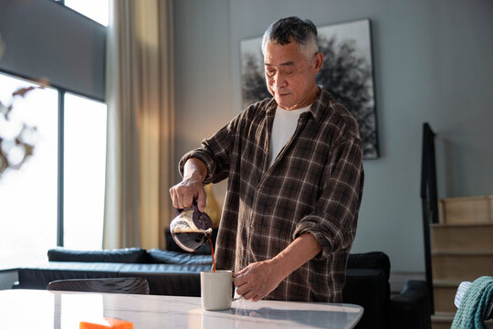 Man pours coffee in modern, minimalist home setting.