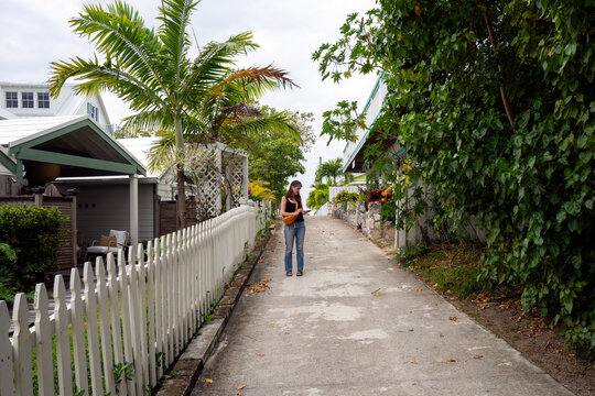 Tourist uses phone while walking on a street in Elbow Cay, Bahamas