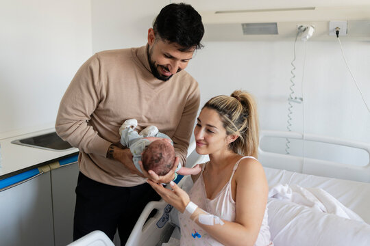 New parents bonding with newborn baby in hospital room
