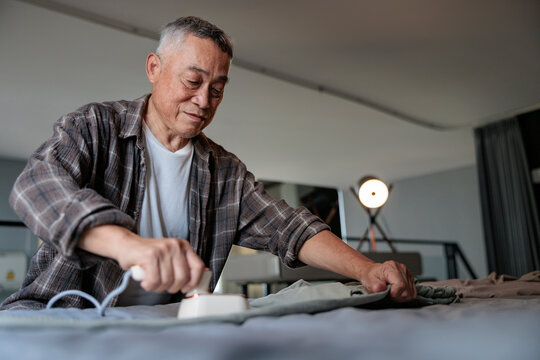 Older man carefully irons clothes on a flat surface.
