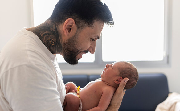 Tattooed father bonding with newborn baby after birth