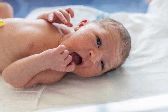 Newborn baby opening mouth, looking with innocent eyes