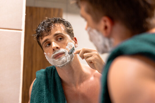 Man shaving his beard in the bathroom