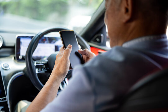 Senior man using a smartphone in the driver's seat of a car