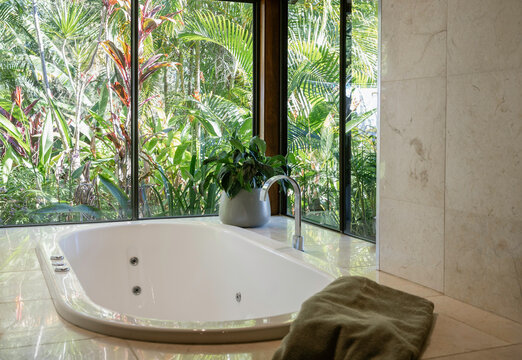 Spa bath with windows looking onto a lush green garden in Australia