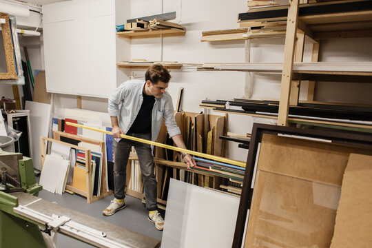 Man choosing picture frame molding in workshop