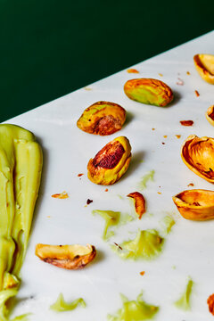 pistachio shells sit beside a cropped green spread on a table