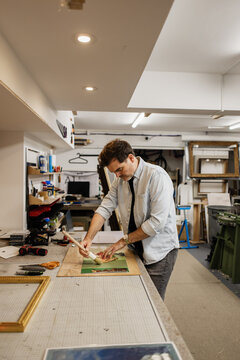 Man framing artwork in professional workshop