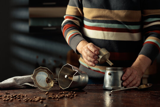 A man in a striped jumper is about to make coffee in an old Italian coffee maker.
