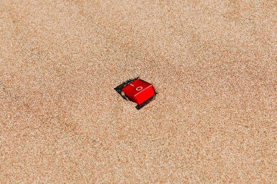 a red power switch is set to on in empty beach sand