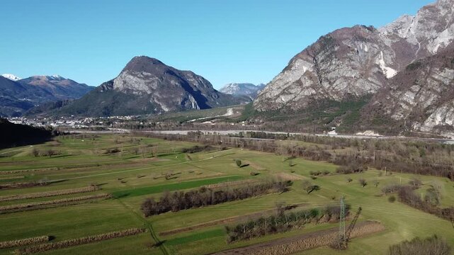 Horizontal 2.7K 30fps aerial shot of the green Carnic Alps mountains in Cavazzo Carnico, Italy. Beautiful sunny day with a clear blue sky over the mountain landscape