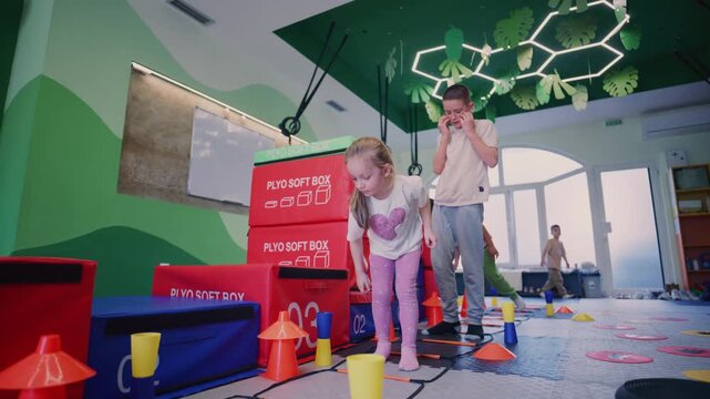 Young children enthusiastically participate in a dynamic fitness training session at an indoor gym, showcasing their agility and coordination.