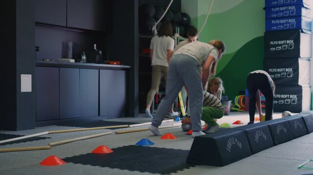 Children participate in an engaging indoor fitness class, developing coordination and physical skills. Young boys and girls are actively involved in a sports training session with cones and balls.