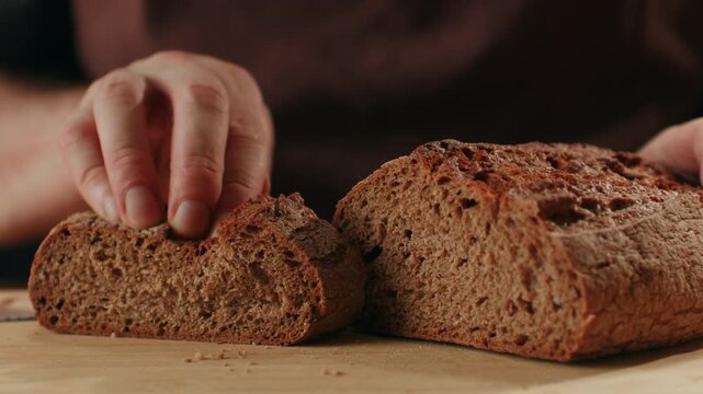 Black rye bread close up, cutting with knife dark brown sliced loaf, borodinsky slavic food, square slices with coriander on white background, baker with tasty healthy fresh bread.