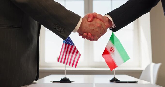 Handshake diplomacy agreement negotiation treaty by diplomats. USA and Iran flags stand by documents during cordial meeting. Symbolizes international politics diplomacy and bilateral agreement.