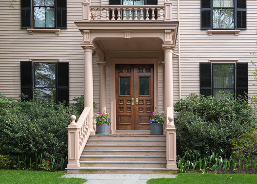 Front entrance with double wood grain doors of pastel colored clapboard house