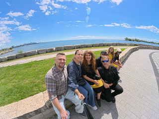 Obraz premium happy family portrait by lake ontario with toronto skyline, happy family taking selfie with toronto skyline and lake ontario in the background. summer day, travel, family vacation and outdoor lifestyl