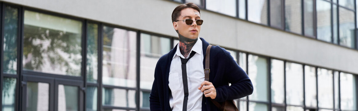 Stylish man with tattoos and sunglasses strolls confidently by a modern architectural structure