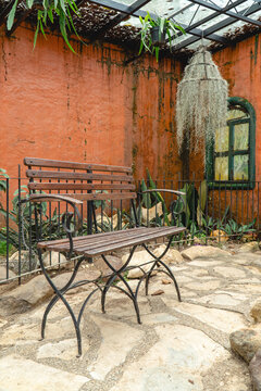 Rustic outdoor patio with vintage metal tables and chairs beside a brick wall, featuring ornamental plants and decorative elements in West Java, Indonesia.