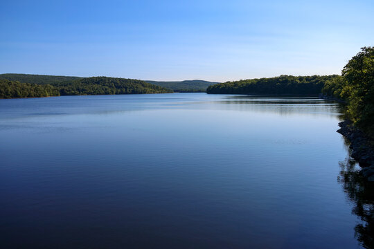 Scenic view of Lake Scranton surrounded by dense green forest mountains under a clear blue sky