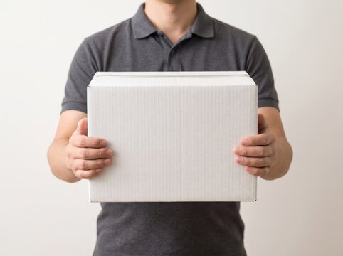 Man holding plain white cardboard delivery box for shipping or product package design with delivery, shipping