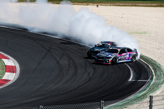 Two cars drift action challenge, drifting on racetrack with large amount of smoke