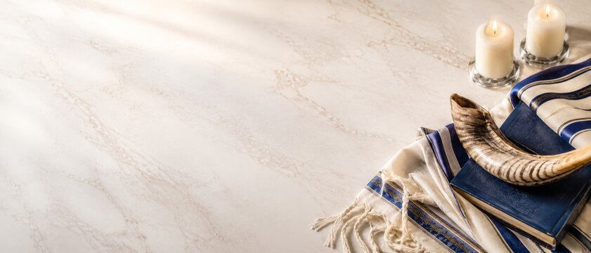 Jewish prayer book with candles and shofar against a bright background for high holy banner format