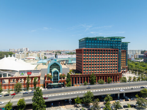 LISBON, PORTUGAL - JUNE 28, 2026: Drone shot of the modern architecture of Centro Colombo shopping mall, BNP Paribas office building, and adjacent highway during a sunny day.