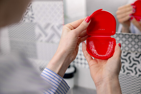 woman holding box with transparent invisible dental aligners for teeth straightening