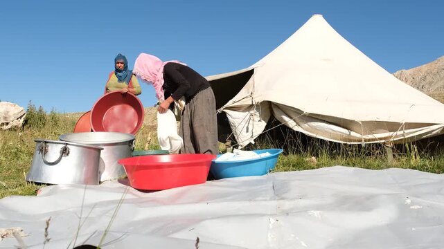 A woman works with basins, pots, and cloths during traditional cheese making in the highlands, showing handmade rural production, open-air preparation, and an authentic pastoral lifestyle.
