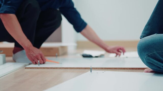 Couple Assembling Flat Pack Furniture Together at Home Using Electric Screwdriver on Floor