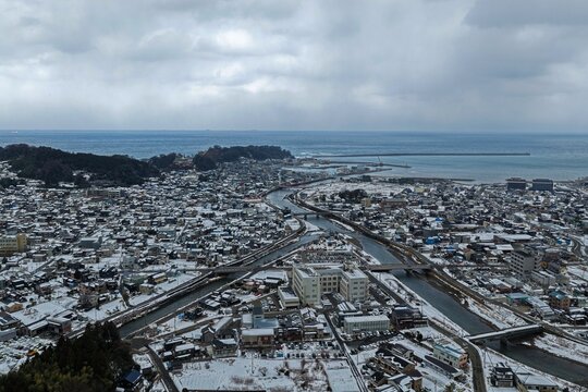 Aerial drone photo of snow-covered Wajima city and river flowing to the sea, Ishikawa, Japan