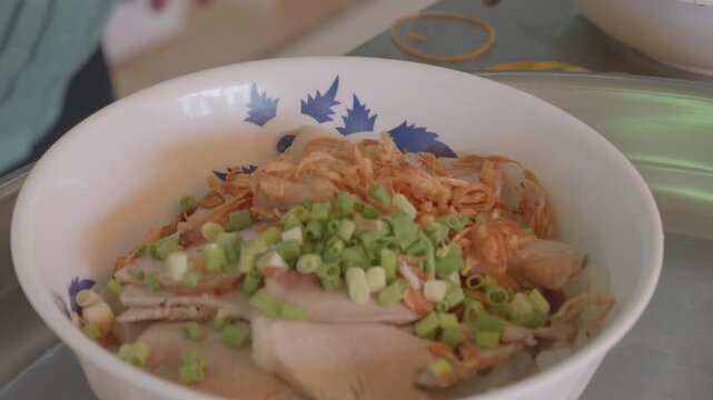 Close-up of Adding Fried Shallots and Scallions to a Bowl of Vietnamese Banh Canh