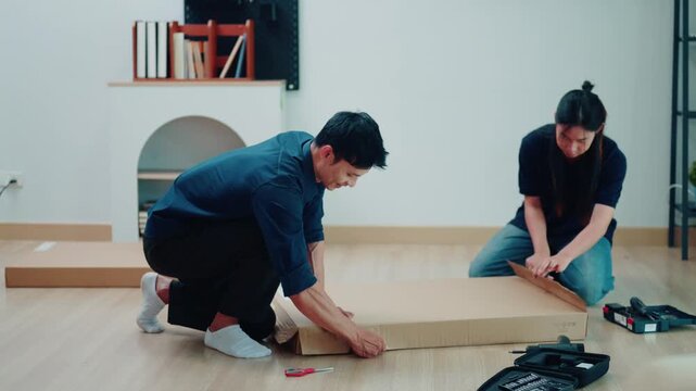 Asian Couple Assembling Flat Pack Furniture Together on Living Room Floor