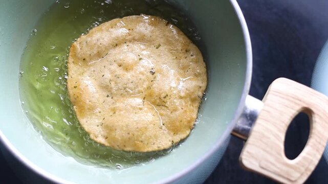 Indian bread or puri or pudi being fried in hot oil