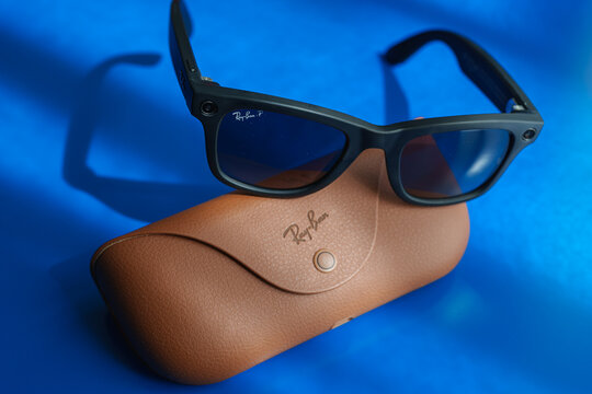 Dusseldorf, Germany - July 9 2026: Ray-Ban Meta Wayfarer smart glasses resting on the official protective carrying case on a blue desk