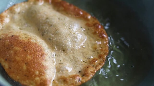 Indian bread or puri or pudi being fried in hot oil