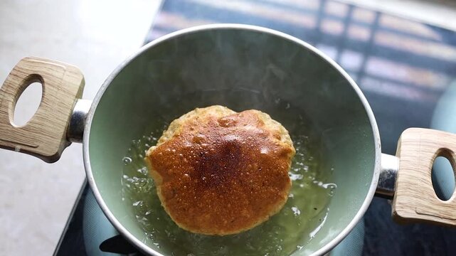 Indian bread or puri or pudi being fried in hot oil